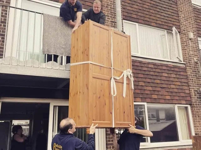 Reliable Removals crew lowering a wardrobe from a first floor balcony